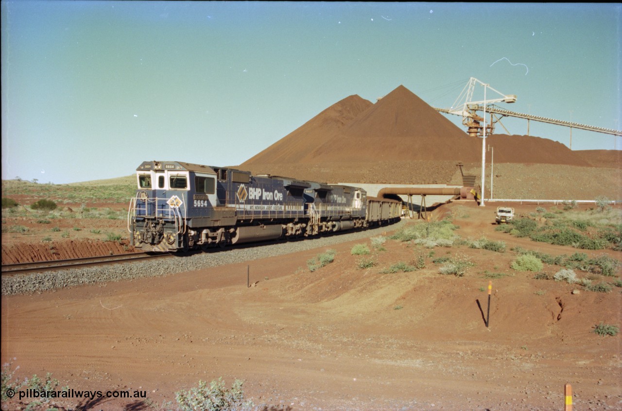 230-26
Yandi Two balloon loop, view of the stockpile area and pedestal stacker, train being loaded at 1.2 km/h behind two Goninan GE CM40-8M rebuilds from different ALCo builders. 5654 'Kashima' serial 8412-11/93-145 is from Comeng ALCo M636 unit 5493 while 5637 'De Grey' serial 8181-01/92-123 is from an AE Goodwin ALCo C636 unit 5456. Geodata [url=https://goo.gl/maps/h68ia1caJvL2] -22.718338, 119.039909 [/url].
Keywords: 5654;Goninan;GE;CM40-8M;8412-11/93-145;rebuild;Comeng-NSW;ALCo;M636C;5493;C6084-9;