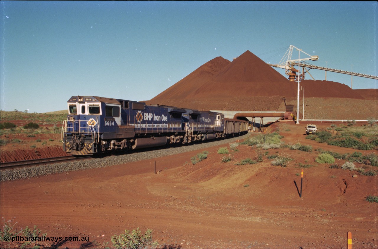 230-27
Yandi Two balloon loop, view of the stockpile area and pedestal stacker, train being loaded at 1.2 km/h behind two Goninan GE CM40-8M rebuilds from different ALCo builders. 5654 'Kashima' serial 8412-11/93-145 is from Comeng ALCo M636 unit 5493 while 5637 'De Grey' serial 8181-01/92-123 is from an AE Goodwin ALCo C636 unit 5456. Geodata [url=https://goo.gl/maps/h68ia1caJvL2] -22.718338, 119.039909 [/url].
Keywords: 5654;Goninan;GE;CM40-8M;8412-11/93-145;rebuild;Comeng-NSW;ALCo;M636C;5493;C6084-9;