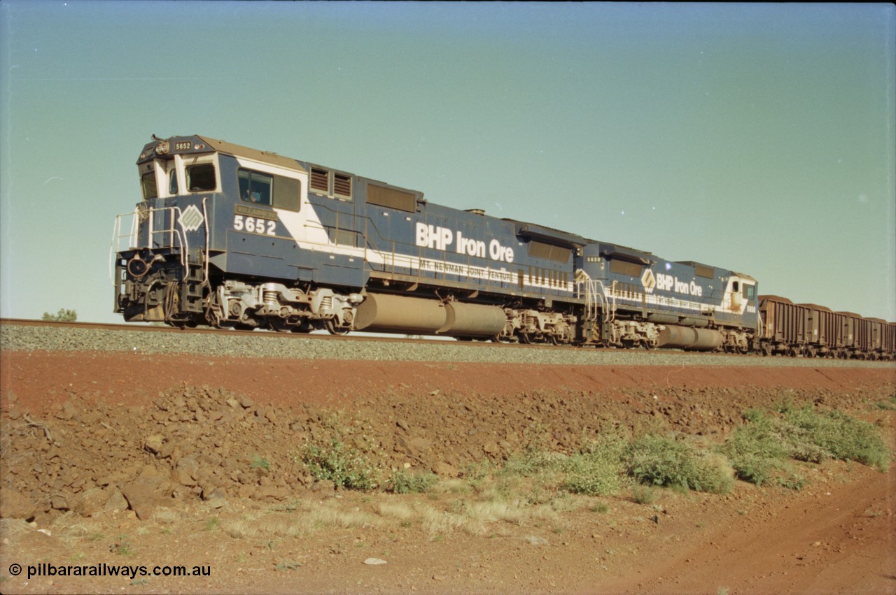 231-03
Yandi Two balloon loop, BHP Iron Ore 5652 'Villanueva' serial 8412-09 / 93-143 an Goninan WA rebuild CM40-8M GE unit loads a train at 1.2 km/h with second unit 5650 'Yawata' serial 8412-07 / 93-141, note the difference in the liveries, 50 is in the teal and marigold logo and logo on the hood while 52 has the silver logo on the front only and no logo on the hood. [url=https://goo.gl/maps/3vQHZqBXNa32]GeoData[/url].
Keywords: 5652;Goninan;GE;CM40-8M;8412-09/93-143;rebuild;AE-Goodwin;ALCo;M636C;5482;G6061-3;