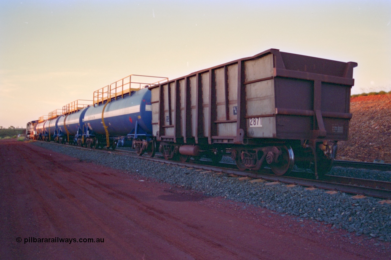 232-19
Yandi One backtrack, following a cyclone shutdown of the mainline and severe flooding around Yandi a 'mixed' freight train was operated to Yandi to deliver food, mail and diesel fuel to the mine and camp. Here BHP Iron Ore loaded Comeng WA built ore waggon 2871 has been re-sheeted with 3CR12 stainless steel side walls. February 1997. [url=https://goo.gl/maps/6c1WFqjYSg42]GeoData[/url].
Keywords: 2871;Comeng-WA;