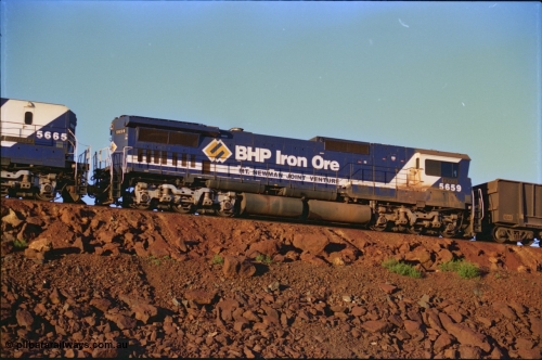 232-08
Yandi One balloon loop, mid-train remote units of train no. 1718 which is partway through loading, BHP Iron Ore unit 5659 'Kobe' serial 8412-04 / 94-150 leads cab-less unit 5665, both are Goninan rebuild CM40-8M GE units, 59 is still in the teal and marigold logo livery. 3rd of February 1997. [url=https://goo.gl/maps/JhTwdFuTRZo]GeoData[/url].
Keywords: 5659;Goninan;GE;CM40-8M;8412-04/94-150;rebuild;AE-Goodwin;ALCo;M636C;5483;G6061-4;