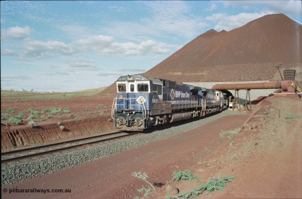 233-16
Yandi Two exit portal or loaded car side of load-out tunnel, the Yandi Two load-out has two load-out stations or vaults to allow to different products to be loaded. Only one vault is used at a time. A loading train lead by BHP Iron Ore's Goninan rebuild CM40-8M GE unit 5650 'Yawata' serial 8412-07 / 93-141 as it drags the train through at 1.2 km/h with assistance from two sister units. [url=https://goo.gl/maps/RgJfYGtPXb52]GeoData[/url].
Keywords: 5650;Goninan;GE;CM40-8M;8412-07/93-141;rebuild;AE-Goodwin;ALCo;M636C;5481;G6061-2;