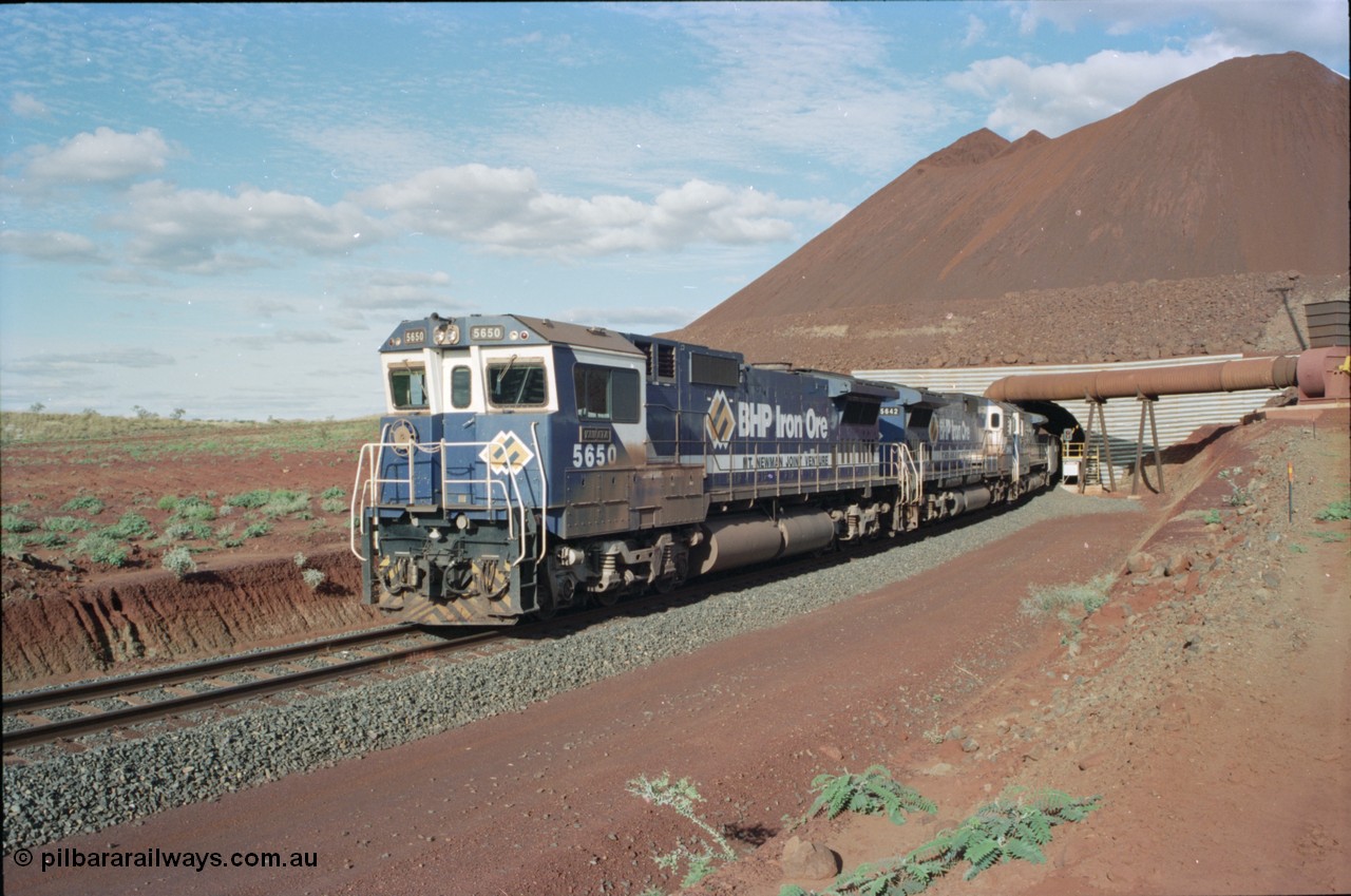 233-17
Yandi Two exit portal or loaded car side of load-out tunnel, the Yandi Two load-out has two load-out stations or vaults to allow to different products to be loaded. Only one vault is used at a time. A loading train lead by BHP Iron Ore's Goninan rebuild CM40-8M GE unit 5650 'Yawata' serial 8412-07 / 93-141 as it drags the train through at 1.2 km/h with assistance from two sister units. [url=https://goo.gl/maps/RgJfYGtPXb52]GeoData[/url].
Keywords: 5650;Goninan;GE;CM40-8M;8412-07/93-141;rebuild;AE-Goodwin;ALCo;M636C;5481;G6061-2;