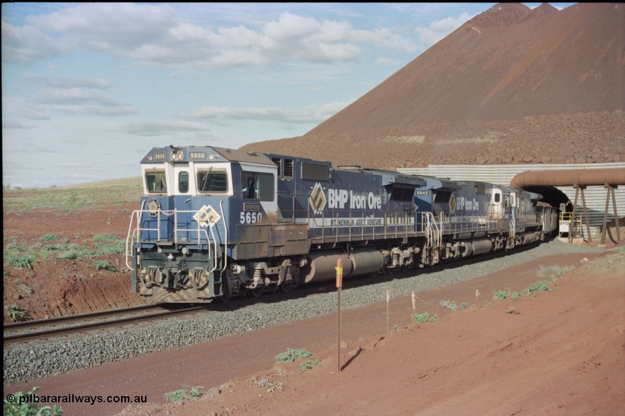 233-18
Yandi Two exit portal or loaded car side of load-out tunnel, the Yandi Two load-out has two load-out stations or vaults to allow to different products to be loaded. Only one vault is used at a time. A loading train lead by BHP Iron Ore's Goninan rebuild CM40-8M GE unit 5650 'Yawata' serial 8412-07 / 93-141 as it drags the train through at 1.2 km/h with assistance from two sister units. [url=https://goo.gl/maps/RgJfYGtPXb52]GeoData[/url].
Keywords: 5650;Goninan;GE;CM40-8M;8412-07/93-141;rebuild;AE-Goodwin;ALCo;M636C;5481;G6061-2;