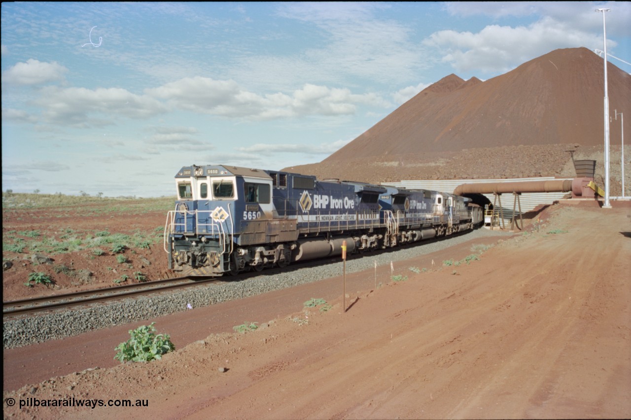 233-19
Yandi Two exit portal or loaded car side of load-out tunnel, the Yandi Two load-out has two load-out stations or vaults to allow to different products to be loaded. Only one vault is used at a time. A loading train lead by BHP Iron Ore's Goninan rebuild CM40-8M GE unit 5650 'Yawata' serial 8412-07 / 93-141 as it drags the train through at 1.2 km/h with assistance from two sister units. [url=https://goo.gl/maps/RgJfYGtPXb52]GeoData[/url].
Keywords: 5650;Goninan;GE;CM40-8M;8412-07/93-141;rebuild;AE-Goodwin;ALCo;M636C;5481;G6061-2;