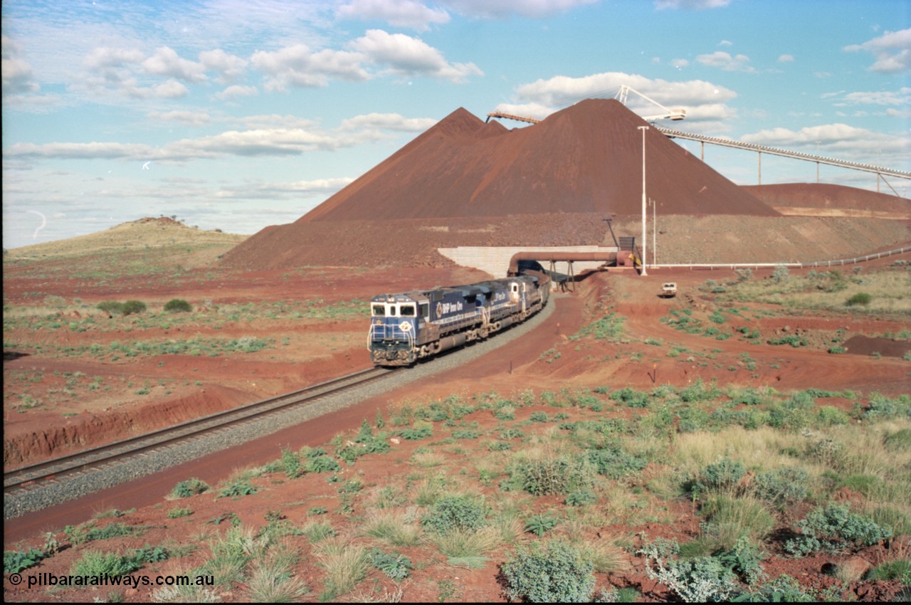 233-22
Yandi Two exit portal or loaded car side of load-out tunnel, the Yandi Two load-out has two load-out stations or vaults to allow to different products to be loaded. Only one vault is used at a time. A loading train lead by BHP Iron Ore's Goninan rebuild CM40-8M GE unit 5650 'Yawata' serial 8412-07 / 93-141 as it drags the train through at 1.2 km/h with assistance from two sister units. [url=https://goo.gl/maps/gXRbfYH9U482]GeoData[/url].
Keywords: 5650;Goninan;GE;CM40-8M;8412-07/93-141;rebuild;AE-Goodwin;ALCo;M636C;5481;G6061-2;