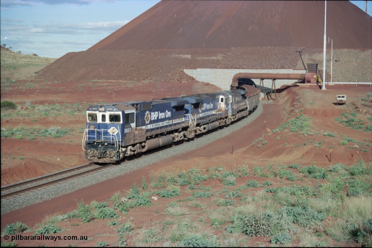 233-23
Yandi Two exit portal or loaded car side of load-out tunnel, the Yandi Two load-out has two load-out stations or vaults to allow to different products to be loaded. Only one vault is used at a time. A loading train lead by BHP Iron Ore's Goninan rebuild CM40-8M GE unit 5650 'Yawata' serial 8412-07 / 93-141 as it drags the train through at 1.2 km/h with assistance from two sister units. [url=https://goo.gl/maps/gXRbfYH9U482]GeoData[/url].
Keywords: 5650;Goninan;GE;CM40-8M;8412-07/93-141;rebuild;AE-Goodwin;ALCo;M636C;5481;G6061-2;