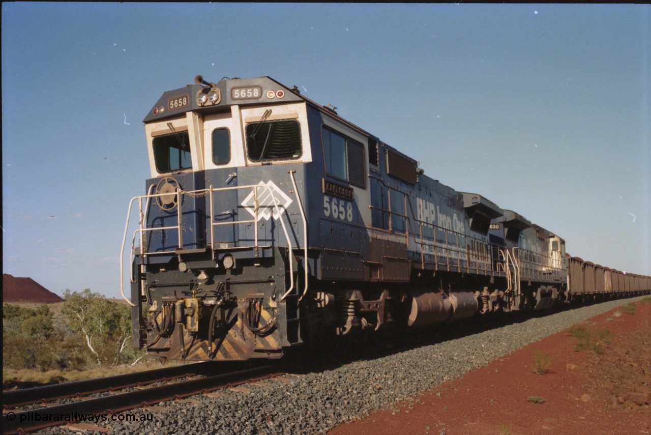 234-18
Yandi Two, BHP Iron Ore Goninan rebuild CM40-8M GE unit 5658 'Kakogawa' serial 8412-03 / 94-149 on the front of a 240 waggon loaded train, this configuration was trialled for a time with two Dash 8 locos, 120 waggons, Dash 8, 120 waggons and Dash 8. Circa 1998.
Keywords: 5658;Goninan;GE;CM40-8M;8412-03/94-149;rebuild;AE-Goodwin;ALCo;M636C;5480;G6061-1;