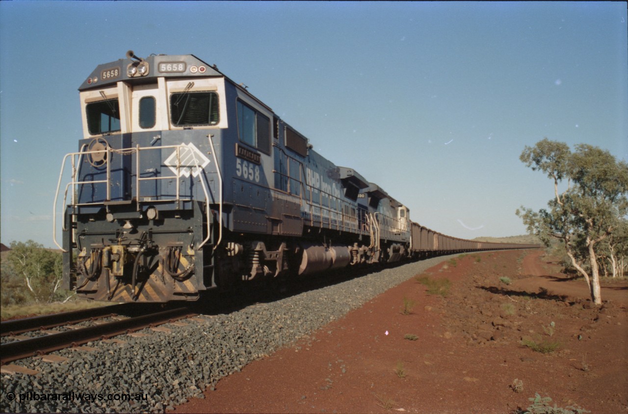 234-28
Yandi Two, BHP Iron Ore Goninan rebuild CM40-8M GE unit 5658 'Kakogawa' serial 8412-03 / 94-149 on the front of a 240 waggon loaded train, this configuration was trialled for a time with two Dash 8 locos, 120 waggons, Dash 8, 120 waggons and Dash 8. Cab front on view. Circa 1998.
Keywords: 5658;Goninan;GE;CM40-8M;8412-03/94-149;rebuild;AE-Goodwin;ALCo;M636C;5480;G6061-1;