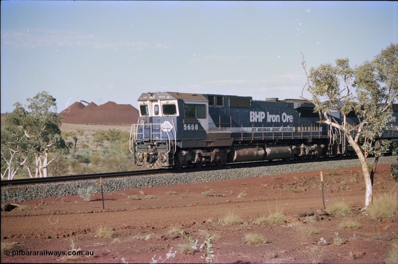 234-31
Yandi Two, BHP Iron Ore Goninan rebuild CM40-8M GE unit 5658 'Kakogawa' serial 8412-03 / 94-149 on the front of a 240 waggon loaded train, this configuration was trialled for a time with two Dash 8 locos, 120 waggons, Dash 8, 120 waggons and Dash 8. View looking from 5658 back to the ore stockpile at the loadout. Circa 1998.
Keywords: 5658;Goninan;GE;CM40-8M;8412-03/94-149;rebuild;AE-Goodwin;ALCo;M636C;5480;G6061-1;