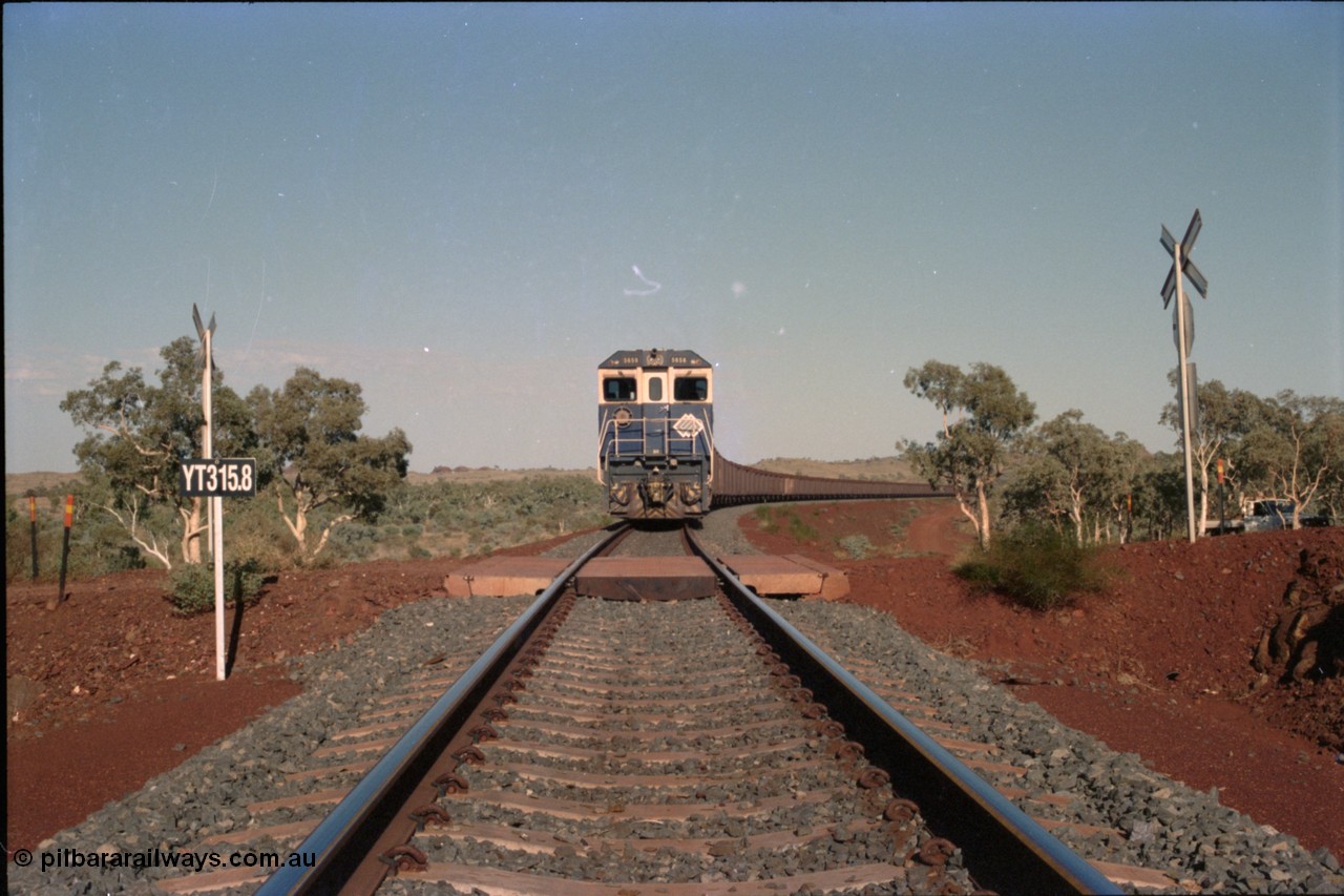 234-35
Yandi Two, BHP Iron Ore Goninan rebuild CM40-8M GE unit 5658 'Kakogawa' serial 8412-03 / 94-149 on the front of a 240 waggon loaded train, this configuration was trialled for a time with two Dash 8 locos, 120 waggons, Dash 8, 120 waggons and Dash 8. View looking across the YT315.8 km grade crossing and 5658 back to the ore stockpile at the loadout. Circa 1998.
Keywords: 5658;Goninan;GE;CM40-8M;8412-03/94-149;rebuild;AE-Goodwin;ALCo;M636C;5480;G6061-1;