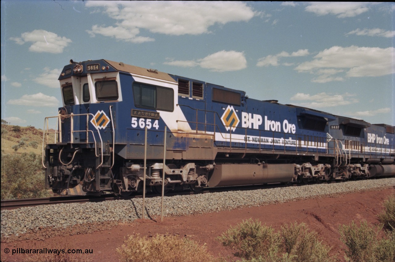 235-19
Yandi One, BHP Iron Ore Goninan rebuild CM40-8M GE unit 5654 'Kashima' serial 8412-11 / 93-145 sits on a loaded train awaiting departure time with second unit also a Goninan GE rebuild 5639 'Corunna Downs' serial 8281-03 / 92-128, note the differences in the two locos as 5653 is rebuilt from a Comeng built ALCo M636 while 5639 was an AE Goodwin built ALCo C636. 5654 also has the late marigold style BHP logo.
Keywords: 5654;Goninan;GE;CM40-8M;8412-11/93-145;rebuild;Comeng-NSW;ALCo;M636C;5493;C6084-9;