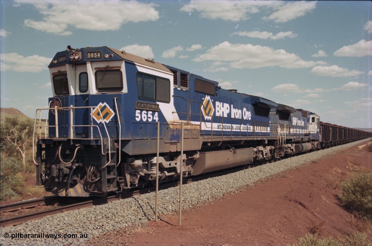 235-21
Yandi One, BHP Iron Ore Goninan rebuild CM40-8M GE unit 5654 'Kashima' serial 8412-11 / 93-145 sits on a loaded train awaiting departure time with second unit also a Goninan GE rebuild 5639 'Corunna Downs' serial 8281-03 / 92-128, note the differences in the two locos as 5653 is rebuilt from a Comeng built ALCo M636 while 5639 was an AE Goodwin built ALCo C636. 5654 also has the late marigold style BHP logo.
Keywords: 5654;Goninan;GE;CM40-8M;8412-11/93-145;rebuild;Comeng-NSW;ALCo;M636C;5493;C6084-9;