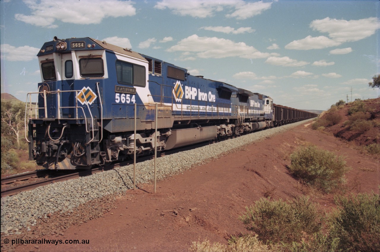 235-22
Yandi One, BHP Iron Ore Goninan rebuild CM40-8M GE unit 5654 'Kashima' serial 8412-11 / 93-145 sits on a loaded train awaiting departure time with second unit also a Goninan GE rebuild 5639 'Corunna Downs' serial 8281-03 / 92-128, note the differences in the two locos as 5653 is rebuilt from a Comeng built ALCo M636 while 5639 was an AE Goodwin built ALCo C636. 5654 also has the late marigold style BHP logo.
Keywords: 5654;Goninan;GE;CM40-8M;8412-11/93-145;rebuild;Comeng-NSW;ALCo;M636C;5493;C6084-9;