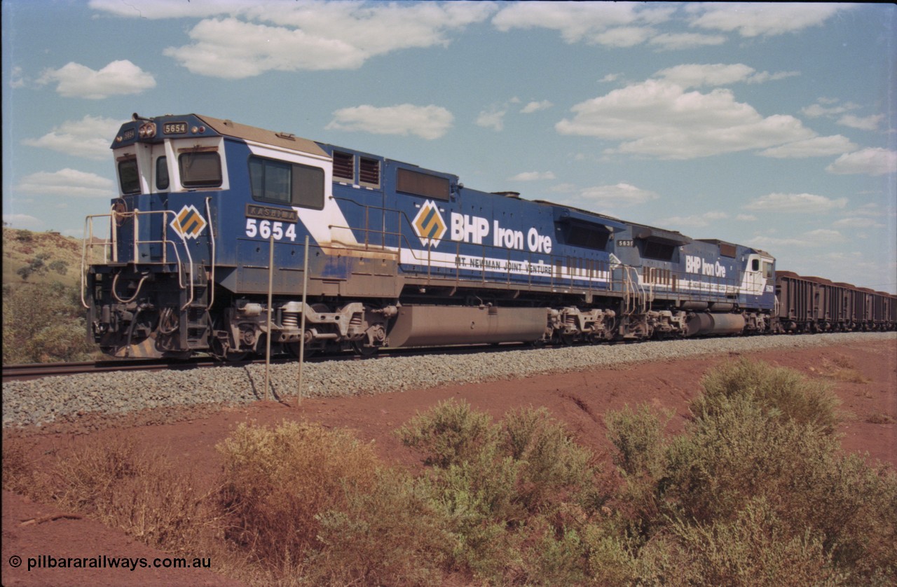 235-29
Yandi One, BHP Iron Ore Goninan rebuild CM40-8M GE unit 5654 'Kashima' serial 8412-11 / 93-145 sits on a loaded train awaiting departure time with second unit also a Goninan GE rebuild 5639 'Corunna Downs' serial 8281-03 / 92-128, note the differences in the two locos as 5653 is rebuilt from a Comeng built ALCo M636 while 5639 was an AE Goodwin built ALCo C636. 5654 also has the late marigold style BHP logo.
Keywords: 5654;Goninan;GE;CM40-8M;8412-11/93-145;rebuild;Comeng-NSW;ALCo;M636C;5493;C6084-9;