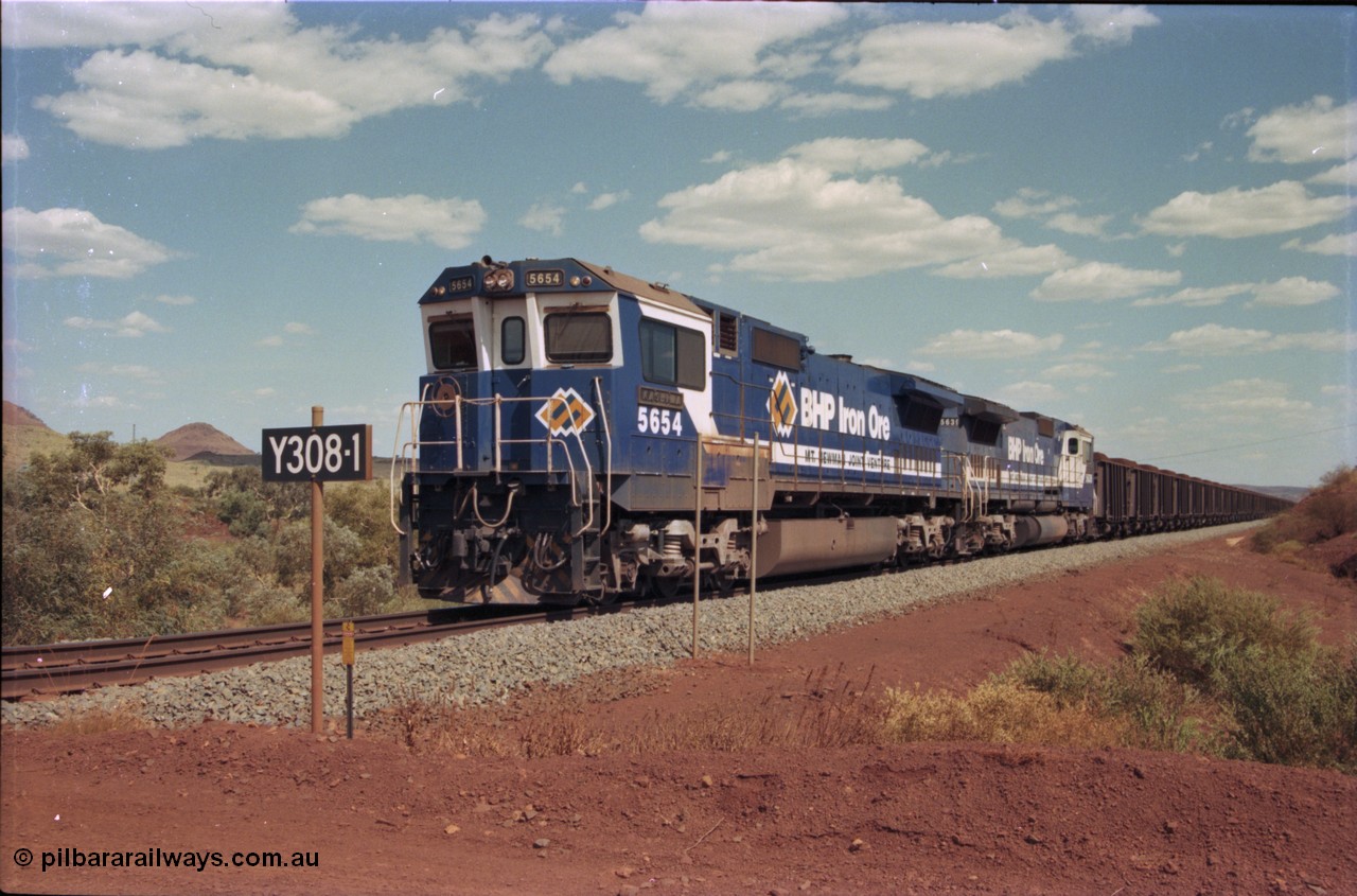 235-30
Yandi One, BHP Iron Ore Goninan rebuild CM40-8M GE unit 5654 'Kashima' serial 8412-11 / 93-145 sits on a loaded train awaiting departure time with second unit also a Goninan GE rebuild 5639 'Corunna Downs' serial 8281-03 / 92-128, note the differences in the two locos as 5653 is rebuilt from a Comeng built ALCo M636 while 5639 was an AE Goodwin built ALCo C636. 5654 also has the late marigold style BHP logo.
Keywords: 5654;Goninan;GE;CM40-8M;8412-11/93-145;rebuild;Comeng-NSW;ALCo;M636C;5493;C6084-9;