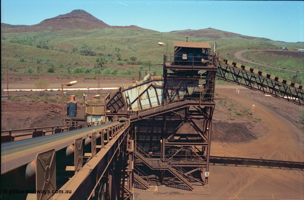 239-14
Overview of the Yandi One Jaques J-Cone secondary crusher and scalping screen as viewed from above the middling crushers, looking down CV6. The conveyor from the right is CV3 from the primary crusher and reclaim tunnel. The bus in the background is parked at the offices and was usually driven by 'Tangles' the sampler. [url=https://goo.gl/maps/2oJ3zTdoX1p]GeoData[/url].
