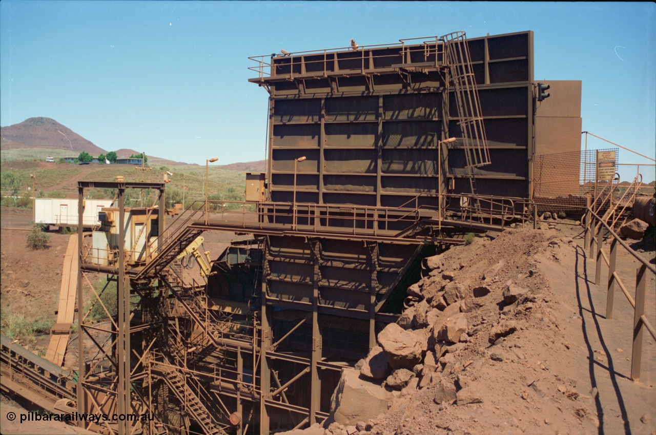 239-21
View from the north western side of the Yandi One ROM (run of Mine) bin showing the operators cabin, Transmin rock breaker, conveyor CV2 running up hill to the left and Sub-Station 1 and the Yandi office complex beyond that on the hill. [url=https://goo.gl/maps/srffXzXYEw22]GeoData[/url].
