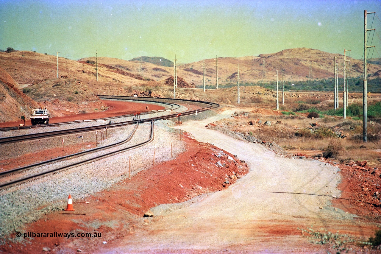 246-04
Cape Lambert, yard view of the then new extension to the south for the West Angelas mine was coming on stream, the just visible siding (rejoining) on the far left will become a compressor waggon holding road, the 6 km and Boat Beach Rd grade crossing are around the corner to the left. Closest to the camera is the extended No. 1 Road which becomes the Empty Car Line from car dumper one for the Deepdale traffic. Next is the original line or Mainline and the third line across is the Loaded Car Line for the West Angelas traffic to the new car dumper 2. The Boat Beach Rd can be seen on the extreme right. 22nd May 2002.
