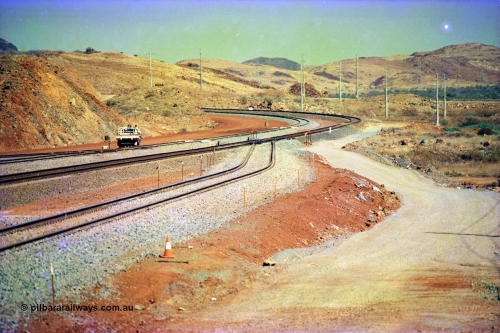 246-03
Cape Lambert, yard view of the then new extension to the south for the West Angelas mine was coming on stream, the just visible siding (rejoining) on the far left will become a compressor waggon holding road, the 6 km and Boat Beach Rd grade crossing are around the corner to the left. Closest to the camera is the extended No. 1 Road which becomes the Empty Car Line from car dumper one for the Deepdale traffic. Next is the original line or Mainline and the third line across is the Loaded Car Line for the West Angelas traffic to the new car dumper 2. 22nd May 2002.
