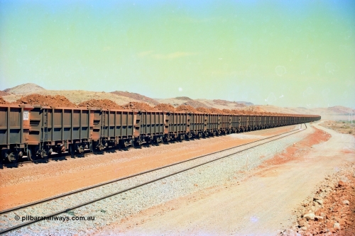 246-30
Cape Lambert, a Robe River loaded Deepdale train rolls along the mainline with the normal 202 waggons which are a mix of builds from Nippon Sharyo Japan and Tomlinson Steel and Centurion Industries both WA companies. The ore is a ROM product and will be dumped over the gyratory crusher to be correctly sized. 22nd May 2002.
