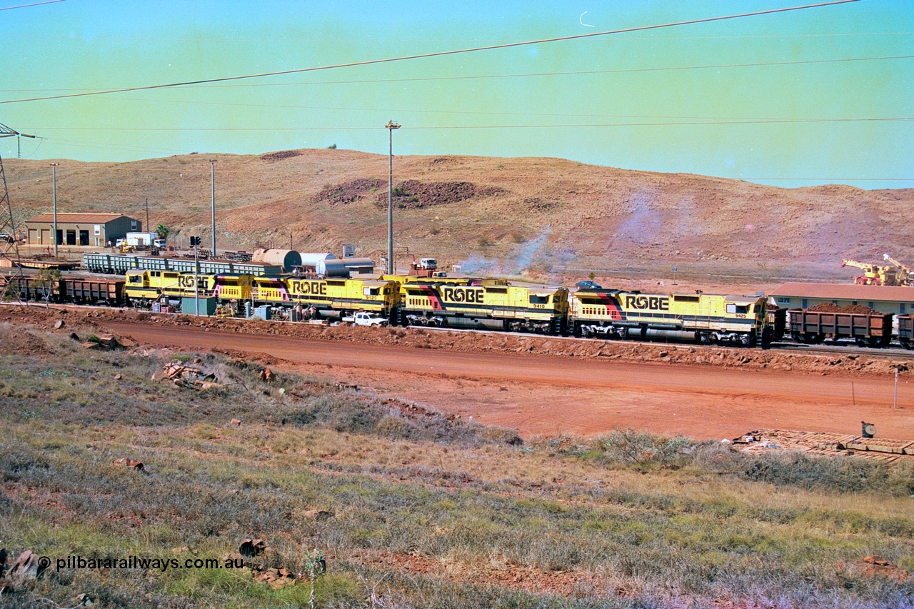 247-23
Cape Lambert overview of the fuel point, with a brace of four Goninan WA CM40-8M GE rebuilds finishing up refuelling before departing with another empty train as a loaded rake is dragged to the dumper behind them. The workshops are to the left of the picture. Where I'm standing to take the picture is now all stockpile. Approximate location of photo is [url=https://goo.gl/maps/B9F4estGGPbd2GrB6]here[/url]. 22nd May 2002.
