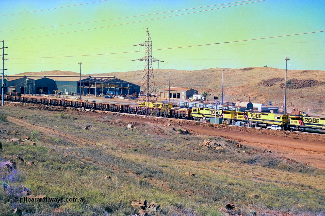 247-24
Cape Lambert overview of the fuel point, with a brace of four Goninan WA CM40-8M GE rebuilds finishing up refuelling before departing with another empty train as a loaded rake is dragged to the dumper behind them. The workshops are to the left of the picture. Where I'm standing to take the picture is now all stockpile. Approximate location of photo is [url=https://goo.gl/maps/B9F4estGGPbd2GrB6]here[/url]. 22nd May 2002.
