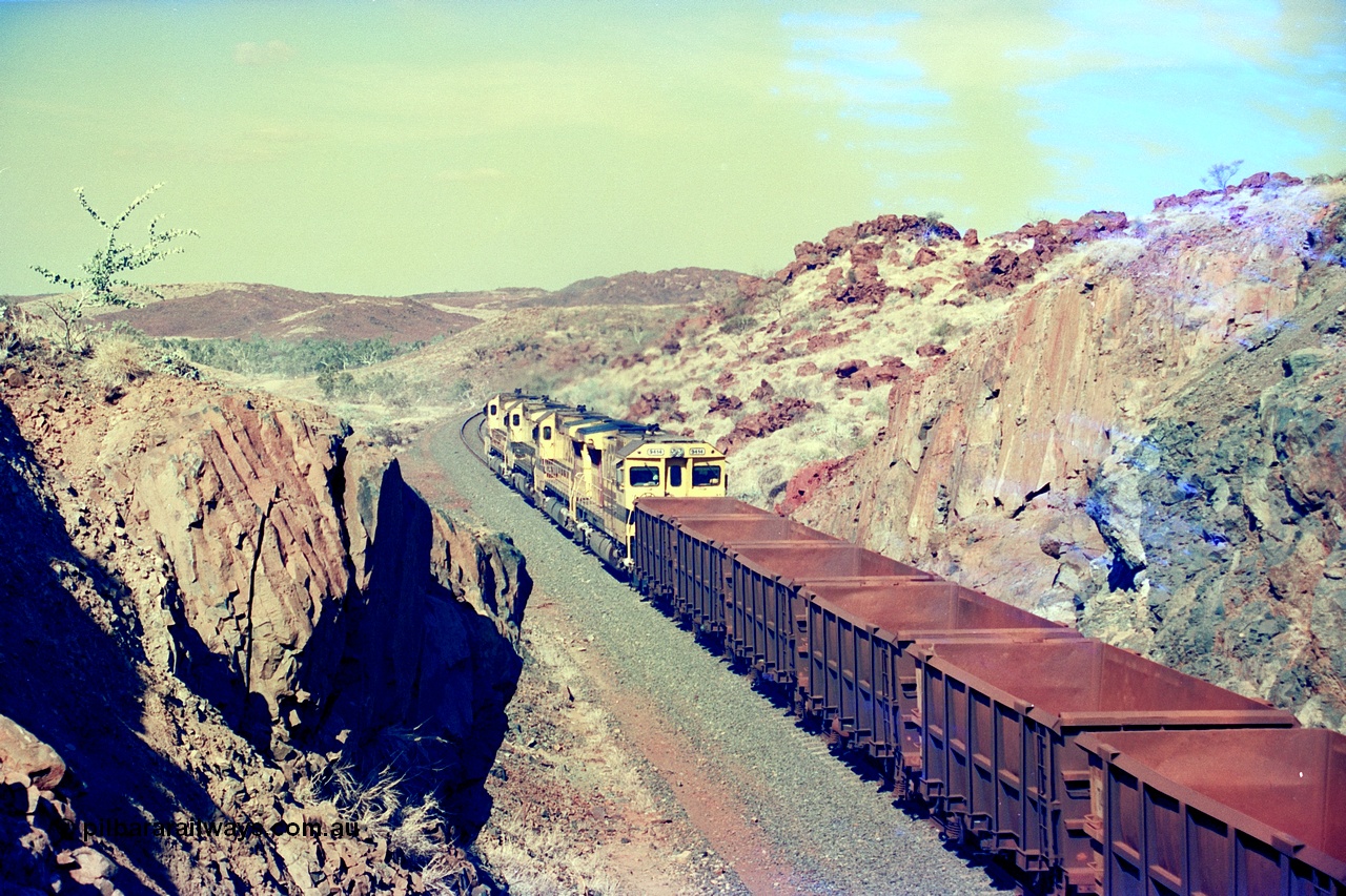 247-35
Near Cooya Pooya at the 37.5 km on the Robe River Cape Lambert line an empty train passes under the town water supply pipeline and pass through Lockyer Gap behind the standard Robe power of quad CM40-8M or Dash 8 locomotives led by 9425 with 9410, 9420 and last unit 9414 which is a Goninan WA ALCo to GE rebuild CM40-8M with serial 8206-11 / 91-124 from November 1991 riding on Dofasco bogies and was originally an AE Goodwin built M636 ALCo built new for Robe in December 1971 and numbered 262.005, later numbered 1714. Location is [url=https://goo.gl/maps/nLyndU6bg2HA5SZX6]here[/url].22nd May 2002.
