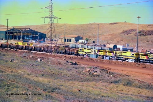 247-25
Cape Lambert overview of the fuel point, with a brace of four Goninan WA CM40-8M GE rebuilds finishing up refuelling before departing with another empty train as a loaded rake is dragged to the dumper behind them. The workshops are to the left of the picture. Where I'm standing to take the picture is now all stockpile. Approximate location of photo is [url=https://goo.gl/maps/B9F4estGGPbd2GrB6]here[/url]. 22nd May 2002.
