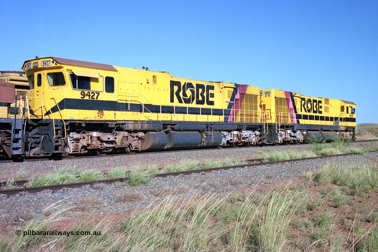 248-18
Seven Mile yard, stored Robe River ALCo locomotives at the south end of the Hamersley Iron Seven Mile yard on roads N2 and N3. On road N2 is 9427 a Comeng WA C636R rebuild from ALCo Schenectady NY model C636 serial 3499-2 originally built in January 1968 for Pennsylvania Railroad as #6331, Penn Central 6331 and finally Conrail 6781. Purchased in 1986 and rebuilt by Comeng WA into C636R before delivery to Robe in January 1987. This loco also went on to become DR 8403 for construction of FMG's railway in 2007-08. Behind it is sister unit 9426. Approximate [url=https://goo.gl/maps/CXwAreRPb2RymQ9m9]location[/url]. 24th April 2004.
Keywords: 9427;Comeng-WA;C636R;WA143-2;rebuild;ALCo;Schenectady-NY;C636;Conrail;6781;3499-2;