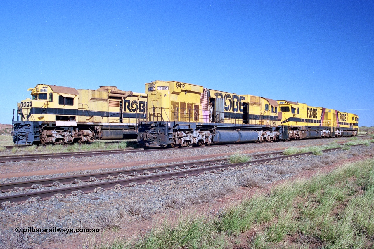 248-20
Seven Mile yard, stored Robe River ALCo locomotives at the south end of the Hamersley Iron Seven Mile yard on roads N2 and N3. On N2 is AE Goodwin built ALCo M636 unit 9412 serial G-6060-3 from December 1971 and originally numbered 262.003 during construction and then 1712 on MLW Dofasco bogies with C636R units 9427 and 9426 on Hi-Ad bogies. Beside it on N3 is 9416 also an AE Goodwin built ALCo M636 serial G-6046-16 from January 1973 and originally numbered 1716 on MLW Dofasco bogies but with a C630 fuel tank in place of the original M636 and larger tank. Approximate [url=https://goo.gl/maps/CXwAreRPb2RymQ9m9]location[/url]. 24th April 2004.
Keywords: 9412;AE-Goodwin;ALCo;M636;G6060-3;