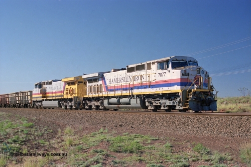 248-01
Dingo Siding on the Hamersley Iron railway at the 39 km with an empty train headed up by a pair of General Electric built Dash 9-44CW units 7077 serial 47756 from the original first order in the Pepsi Can livery and 9408 serial 54158 from the fourth order in the Pilbara Rail livery with Robe ownership markings. Approximate [url=https://goo.gl/maps/Jv752bD5KXv28oUV7]location[/url]. April 24, 2004.
Keywords: 7077;GE;Dash-9-44CW;47756;