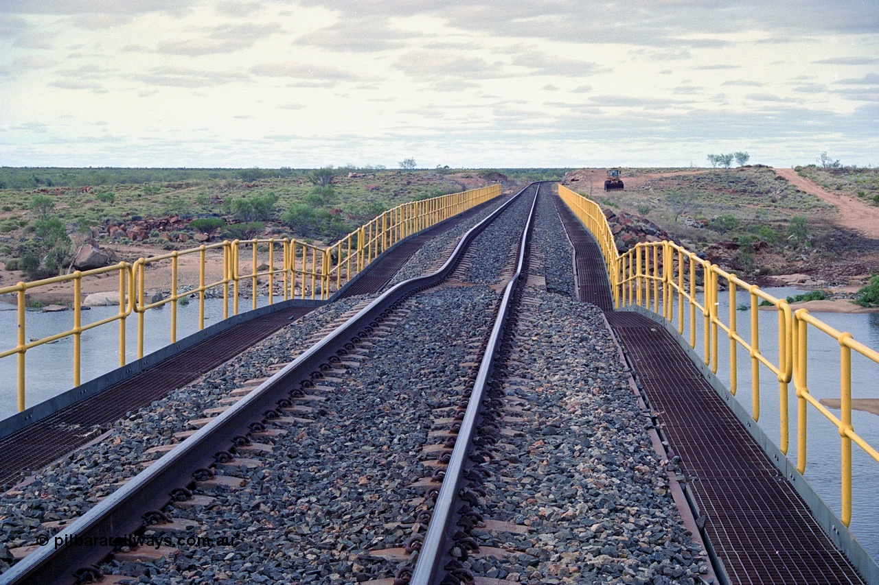 249-04
Yule River bridge looking north from the 160 km on the BHP mainline. The third pier from the southern end was undermined by flood waters from Tropical Cyclone John in December 1999. The rail line was closed for two weeks while repairs were effected. Approximate [url=https://goo.gl/maps/phCWr8u1xnuBdzwj6]location[/url].
