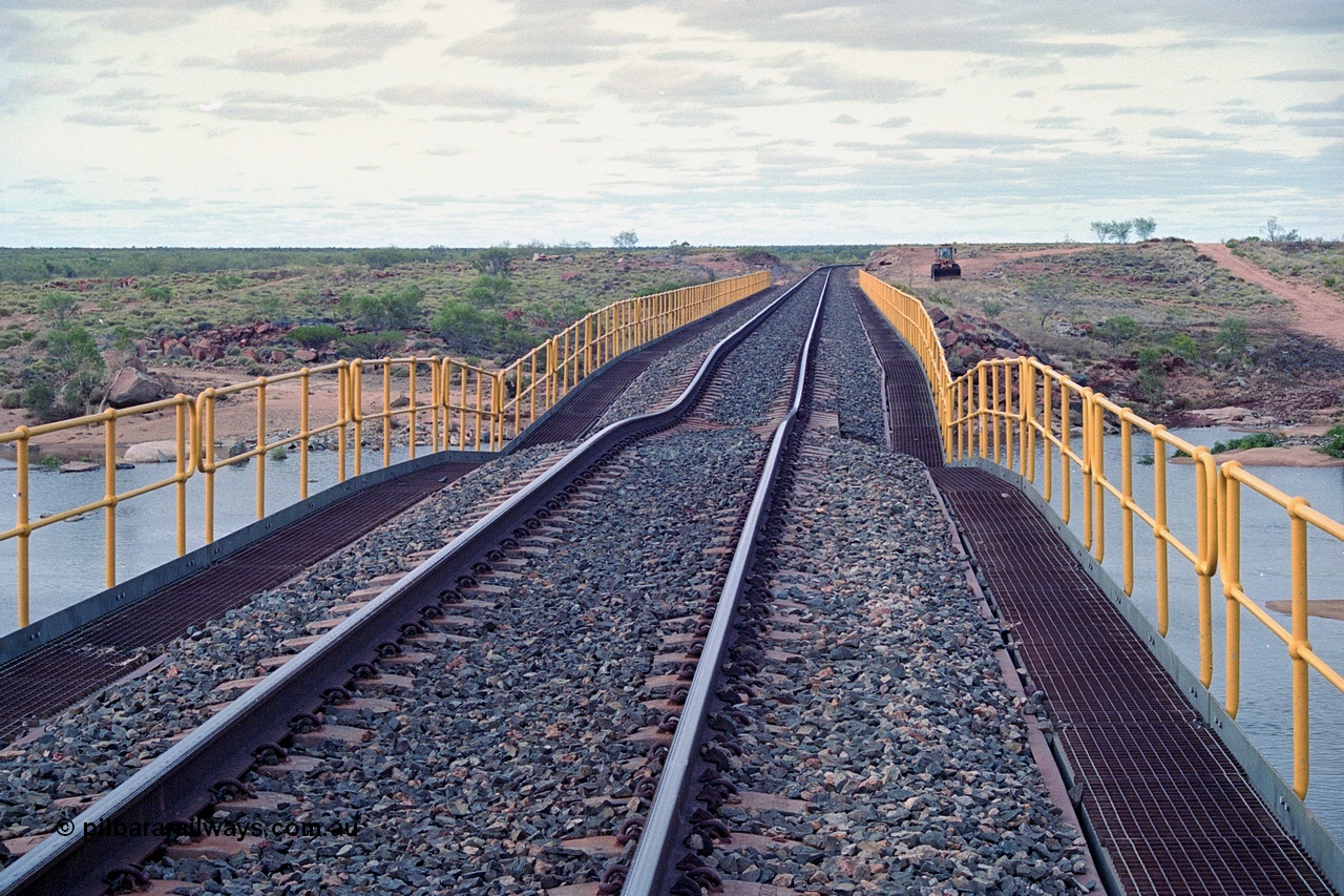 249-05
Yule River bridge looking north from the 160 km on the BHP mainline. The third pier from the southern end was undermined by flood waters from Tropical Cyclone John in December 1999. The rail line was closed for two weeks while repairs were effected. Approximate [url=https://goo.gl/maps/phCWr8u1xnuBdzwj6]location[/url].
