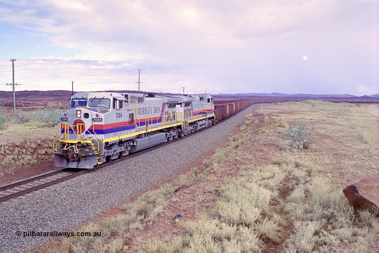 249-31
A loaded Hamersley Iron train runs across the plains north of Dugite Siding near the 70 km as it nears the destination of its cargo behind the standard pair of GE built Dash 9-44CW locomotives 7084 serial 47763 and 7079 serial 47758 both in the original Pepsi Can livery. Approximate [url=https://goo.gl/maps/UUfj15vTkvBaPCaw8]location[/url]. 18th December 1999.
Keywords: 7084;GE;Dash-9-44CW;47763;