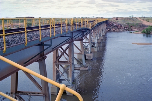 249-03
Yule River bridge looking north from the 160 km on the BHP mainline. The third pier from the southern end was undermined by flood waters from Tropical Cyclone John in December 1999. The rail line was closed for two weeks while repairs were effected. Approximate [url=https://goo.gl/maps/phCWr8u1xnuBdzwj6]location[/url].
