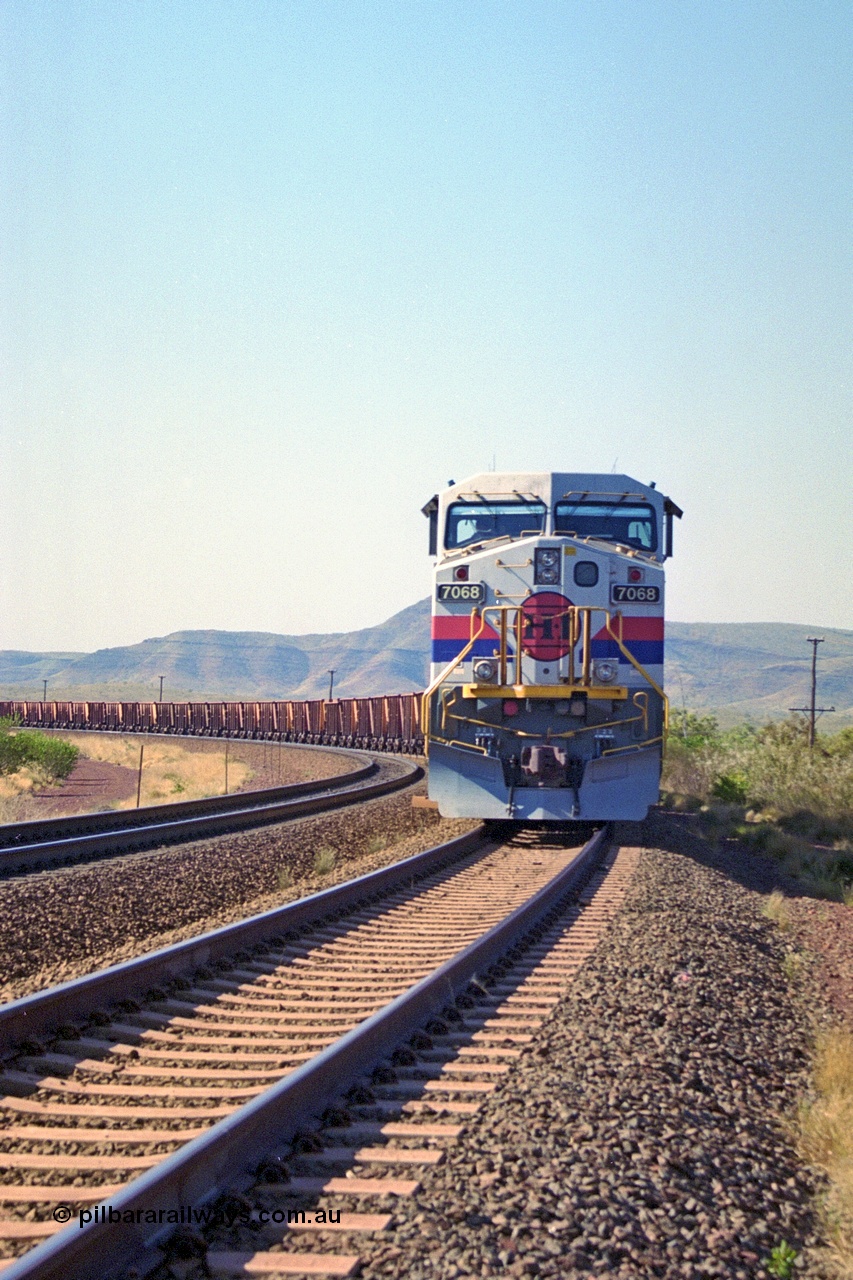 250-02
Pelican Siding on the Hamersley Iron Tom Price line about the 208 km with an empty train behind the standard pairing of two General Electric built 9-44CW units 7068 serial 47747 and 7067 serial 47746 stand on the loop or passing track for a meet with a loaded train. 21st October 2000.
Keywords: 7068;GE;Dash-9-44CW;47747;