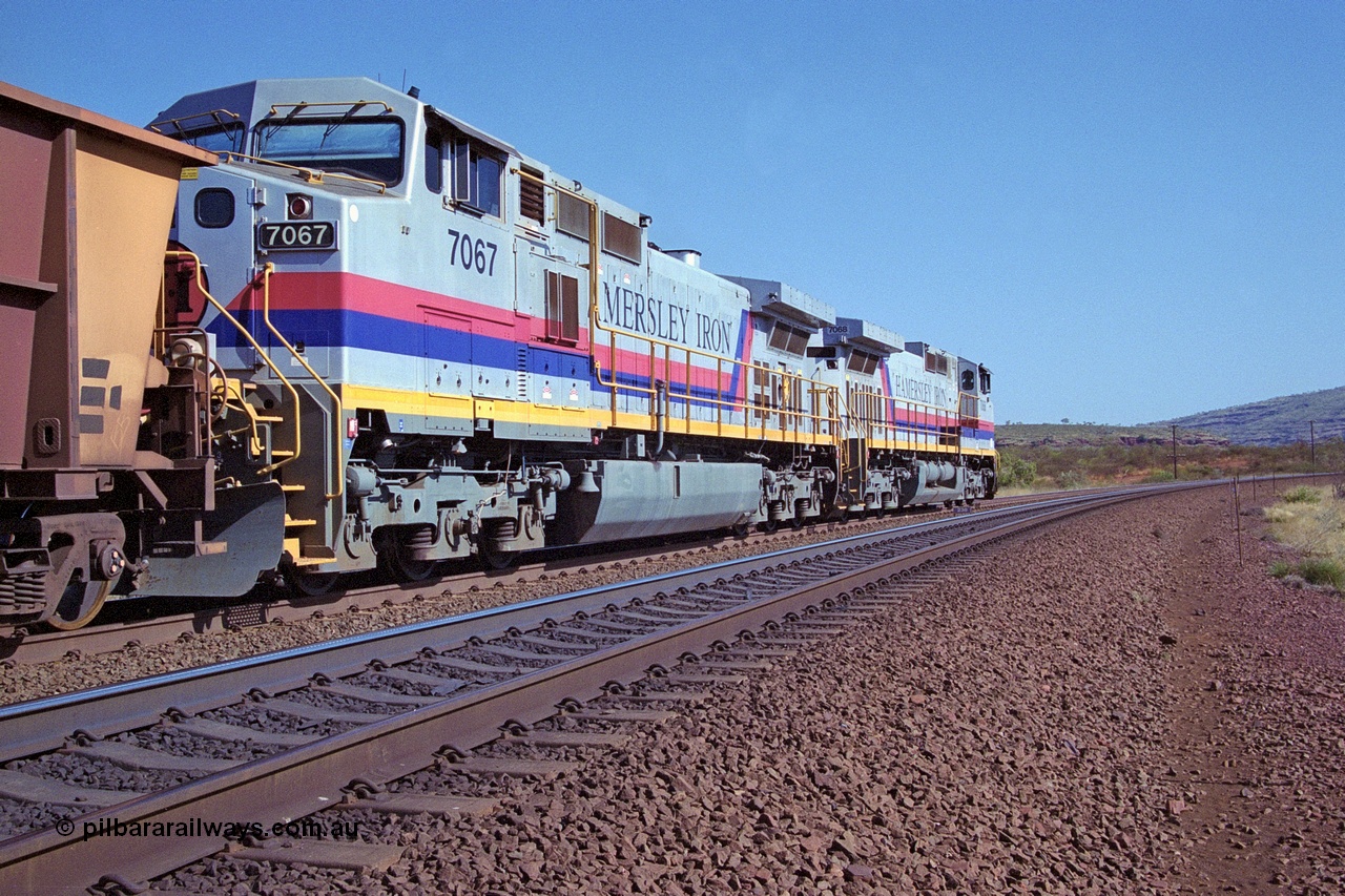 250-05
Pelican Siding on the Hamersley Iron Tom Price line about the 208 km with an empty train behind the standard pairing of two General Electric built 9-44CW units 7068 serial 47747 and 7067 serial 47746 stand on the loop or passing track for a meet with a loaded train. 21st October 2000.
Keywords: 7067;GE;Dash-9-44CW;47746;