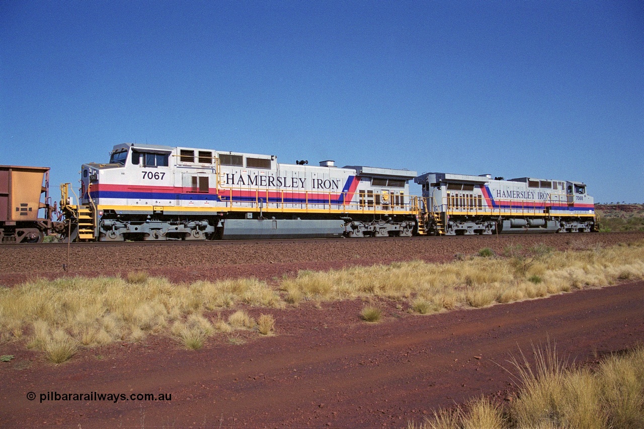 250-06
Pelican Siding on the Hamersley Iron Tom Price line about the 208 km with an empty train behind the standard pairing of two General Electric built 9-44CW units 7068 serial 47747 and 7067 serial 47746 stand on the loop or passing track for a meet with a loaded train. 21st October 2000.
Keywords: 7067;GE;Dash-9-44CW;47746;