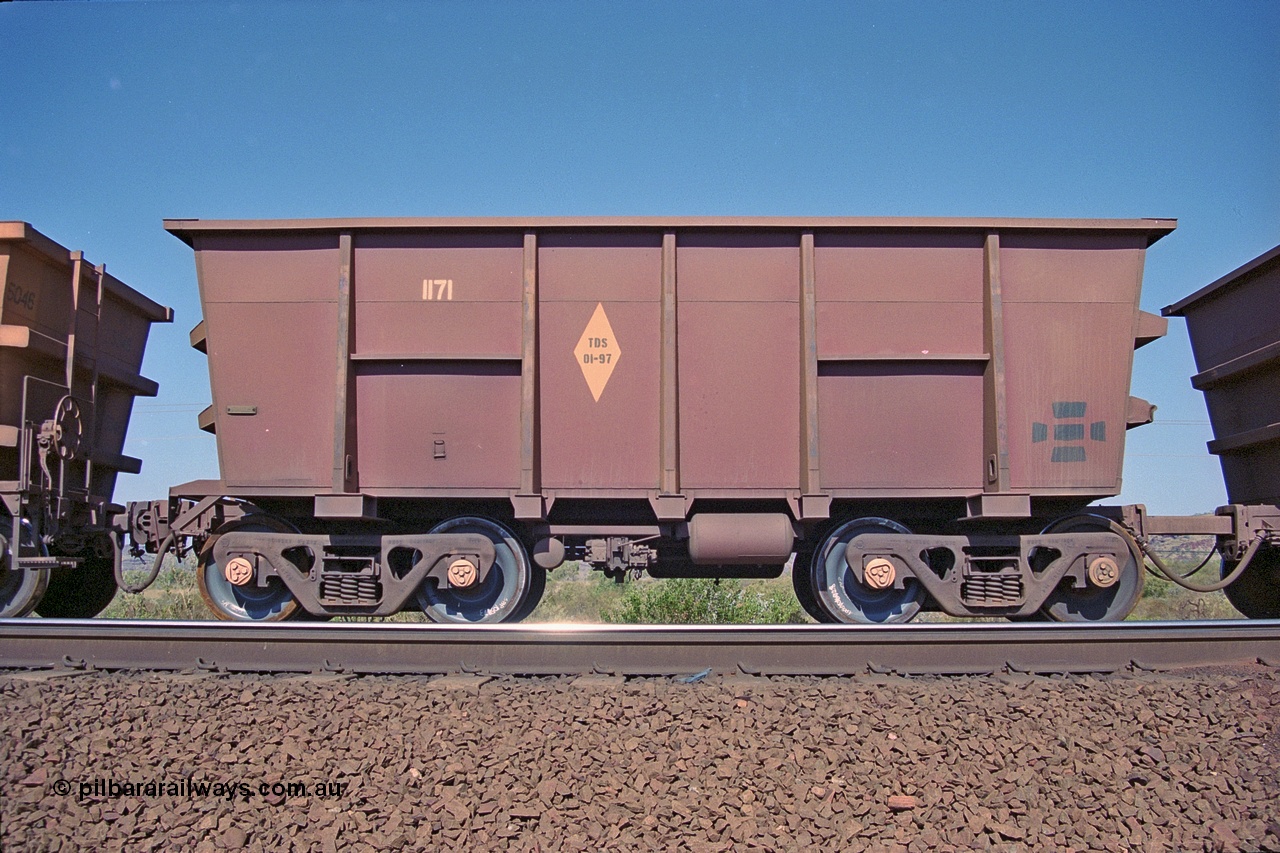 250-08
Pelican Siding on the Hamersley Iron Tom Price line about the 208 km empty ore waggon 1171 is an example of the units built by Tomlinson Steel WA and is a control or master waggon of the pair and shows the re-sheeting paint symbol to indicate that all four sides and the floor have been replaced. Note the square bar coupling on the right hand side to the slave waggon 6085, HI run what they call 'Married Pairs'. 21st October 2000.
Keywords: 1171;Tomlinson-Steel;M-series;