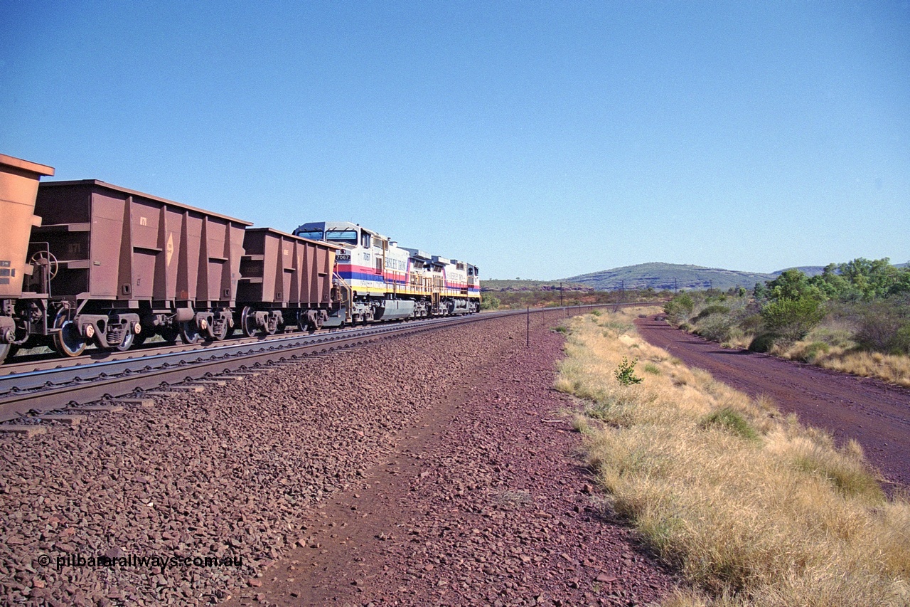250-09
Pelican Siding on the Hamersley Iron Tom Price line about the 208 km with an empty train behind the standard pairing of two General Electric built 9-44CW units 7068 serial 47747 and 7067 serial 47746 stand on the loop or passing track for a meet with a loaded train. 21st October 2000.
