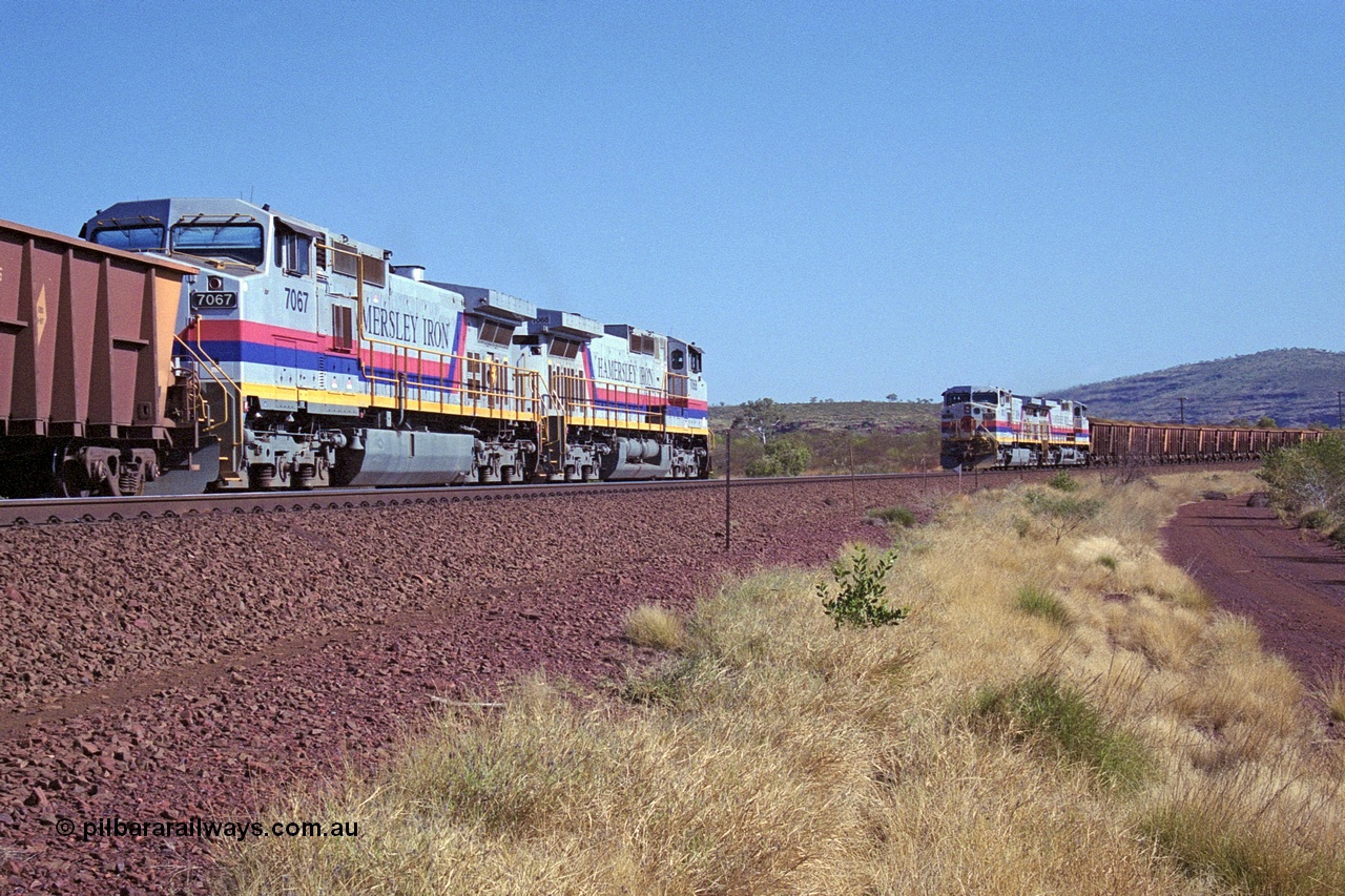 250-10
Pelican Siding on the Hamersley Iron Tom Price line about the 208 km with an empty train behind General Electric built 9-44CW units 7068 serial 47747 and 7067 serial 47746 on the loop as a loaded train with 210 waggons passes behind a sister pairing of 7072 serial 47751 and 7074 serial 47753. 1550 hrs 21st October 2000.
Keywords: 7067;GE;Dash-9-44CW;47746;