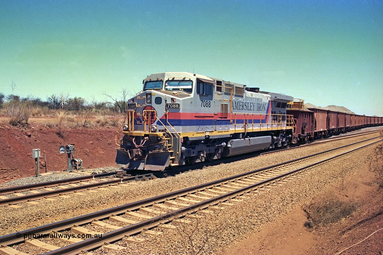 252-05
Cockatoo Siding 273 km on the Hamersley Iron line to Yandi, General Electric built 9-44CW unit 7088 with serial number 47767 from the original 1994 build idles away on the eastern end of the ballast train as it is loaded and slowly progresses into the back track siding Ballast plough BP 02 is behind the locomotive. Location is roughly [url=https://goo.gl/maps/bCvLZxMc1z57F8ym9]here[/url]. 24th November 2001.
Keywords: 7088;GE;Dash-9-44CW;47767;