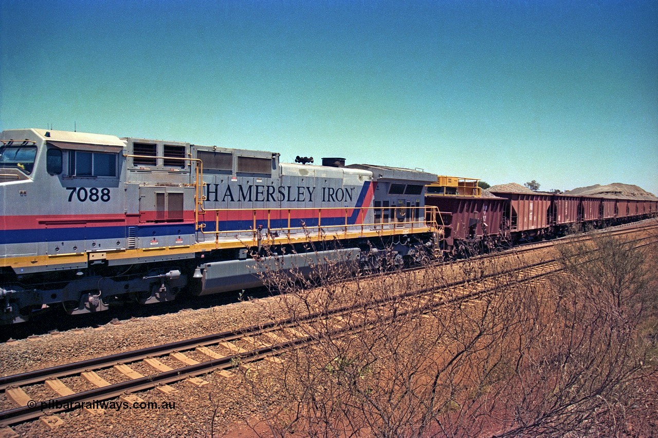 252-09
Cockatoo Siding 273 km on the Hamersley Iron line to Yandi, General Electric built 9-44CW unit 7088 with serial number 47767 from the original 1994 build idles away on the eastern end of the ballast train as it is loaded and slowly progresses into the back track siding Ballast plough BP 02 is behind the locomotive. Location is roughly [url=https://goo.gl/maps/bCvLZxMc1z57F8ym9]here[/url]. 24th November 2001.
Keywords: 7088;GE;Dash-9-44CW;47767;