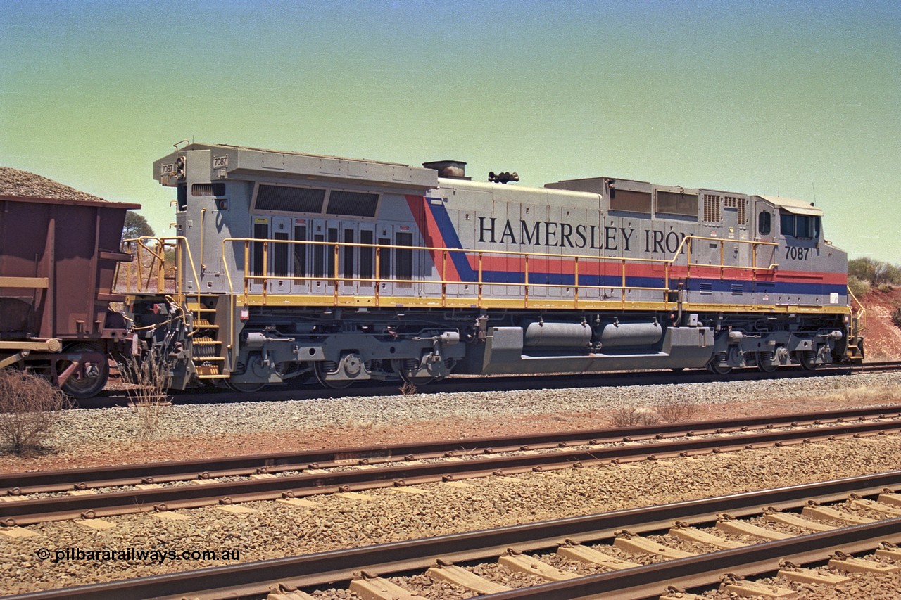 252-12
Cockatoo Siding 273 km on the Hamersley Iron line to Yandi, General Electric built 9-44CW unit 7087 with serial number 47766 from the original 1994 build idles away on the western end of the ballast train as it is loaded and slowly progresses into the back track siding Ballast plough BP 01 is behind the locomotive. Location is roughly [url=https://goo.gl/maps/rNdCHRcDhbQuHTjd7]here[/url]. 24th November 2001.
Keywords: 7087;GE;Dash-9-44CW;47766;