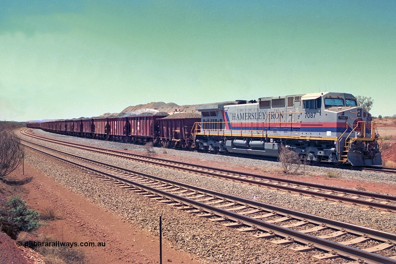 252-14
Cockatoo Siding 273 km on the Hamersley Iron line to Yandi, General Electric built 9-44CW unit 7087 with serial number 47766 from the original 1994 build idles away on the western end of the ballast train as it is loaded and slowly progresses into the back track siding Ballast plough BP 01 is behind the locomotive. Location is roughly [url=https://goo.gl/maps/rNdCHRcDhbQuHTjd7]here[/url]. 24th November 2001.
Keywords: 7087;GE;Dash-9-44CW;47766;