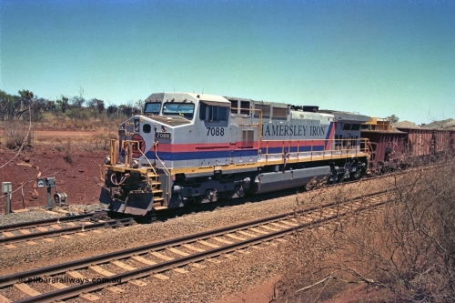 252-03
Cockatoo Siding 273 km on the Hamersley Iron line to Yandi, General Electric built 9-44CW unit 7088 with serial number 47767 from the original 1994 build idles away on the eastern end of the ballast train as it is loaded and slowly progresses into the back track siding Ballast plough BP 02 is behind the locomotive. Location is roughly [url=https://goo.gl/maps/bCvLZxMc1z57F8ym9]here[/url]. 24th November 2001.
Keywords: 7088;GE;Dash-9-44CW;47767;