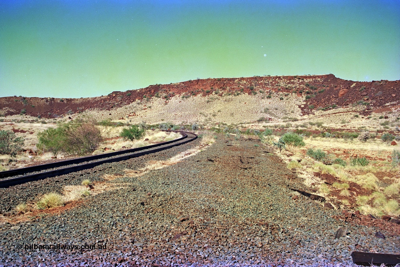 255-16
At the 162.2 km looking south are the remains of the second Robe River loadout facility which was installed in 1975 to mine the Mesa 2402E mining area, the line was a four kilometre U shaped spur curving away to the left. Geodata [url=https://goo.gl/maps/DATgFuHfuayyAp8y9]location here[/url]. May 2002.
