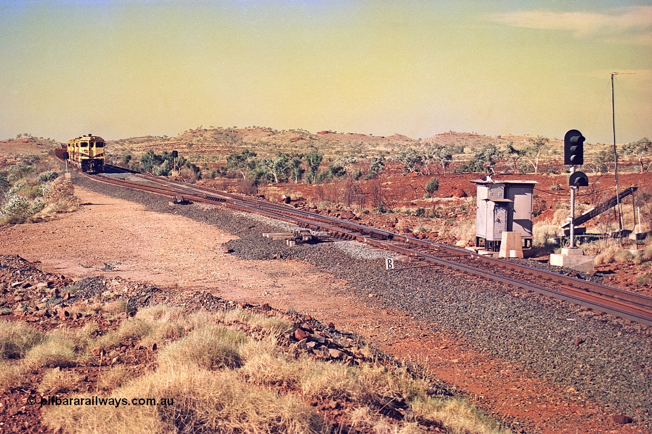 256-05
Maitland Siding located between the 92.8 and 95.1 km on the Cape Lambert line, view of the south end points and swing nose frog with dragging detector bars, solar panel and cabinets for signal and point control with an empty train sitting in the passing track awaiting a meet. May 2002.
