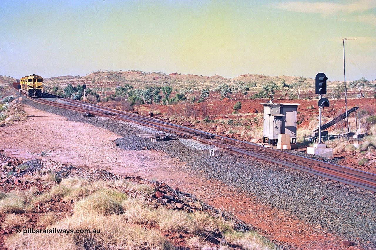 256-06
Maitland Siding located between the 92.8 and 95.1 km on the Cape Lambert line, view of the south end points and swing nose frog with dragging detector bars, solar panel and cabinets for signal and point control with an empty train sitting in the passing track awaiting a meet. May 2002.
